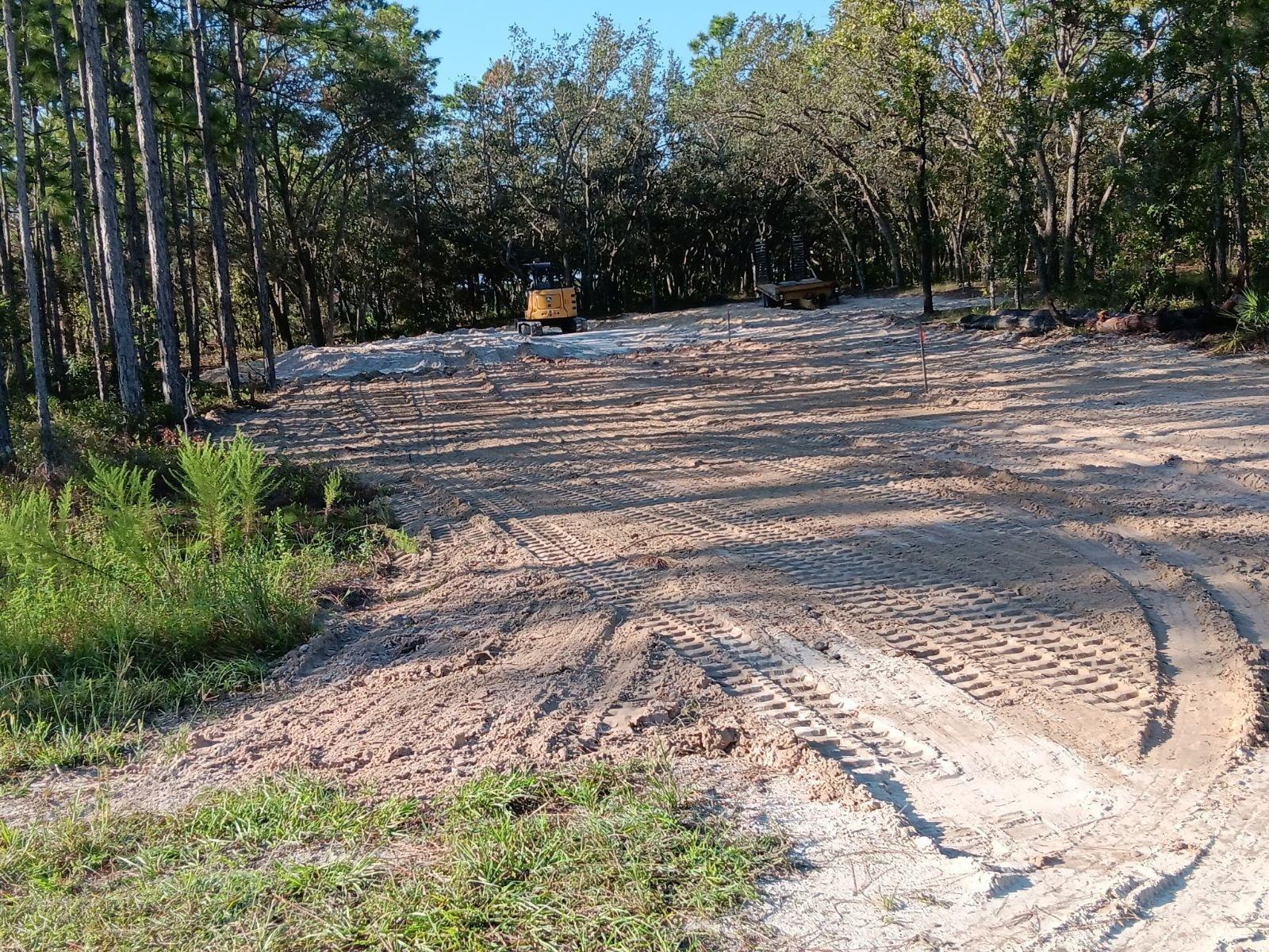 Grading work with machine tracks across sandy ground